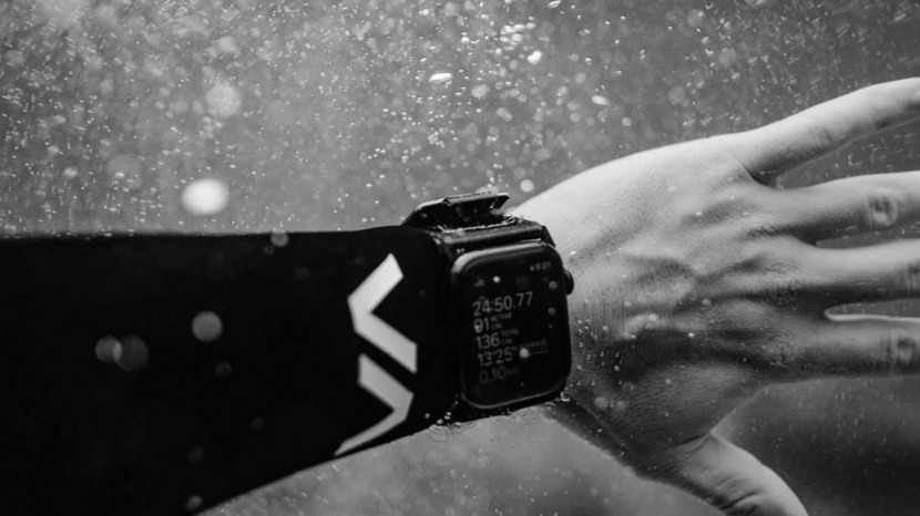 brazo con correa de reloj activa en la muñeca bajo el agua